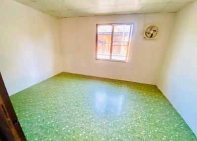 Bright empty bedroom with green flooring and a window