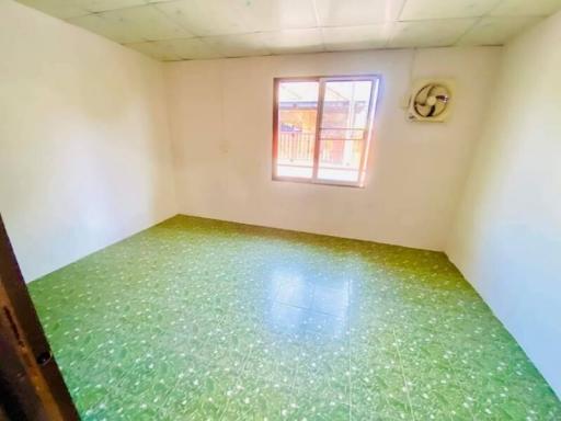 Bright empty bedroom with green flooring and a window