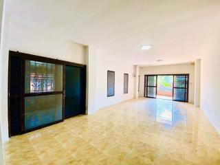 Spacious and well-lit living room with large windows and tiled flooring