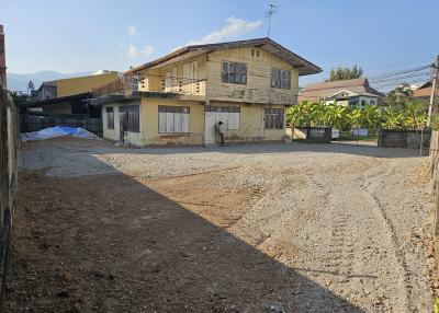 Exterior view of a two-story house with a spacious gravel yard under a clear sky