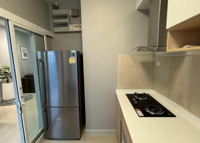 Compact modern kitchen with stainless steel refrigerator and built-in stovetop