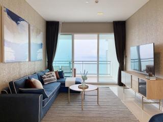 Modern living room with ocean view, featuring stylish furniture and large windows