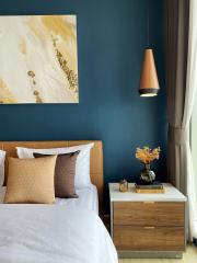 Elegant bedroom with deep blue walls, modern artwork, and stylish nightstand