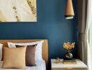 Elegant bedroom with deep blue walls, modern artwork, and stylish nightstand