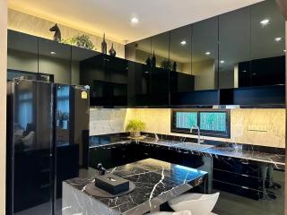 Modern black-themed kitchen with marble countertops and stainless steel appliances