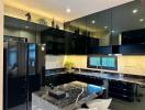 Modern black-themed kitchen with marble countertops and stainless steel appliances