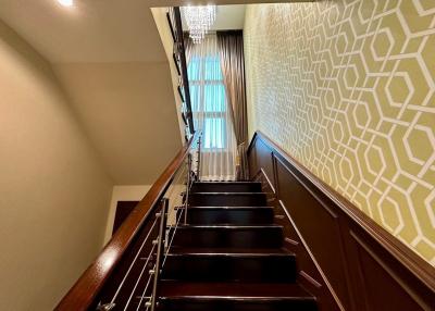 Elegant staircase with chandelier and patterned wallpaper