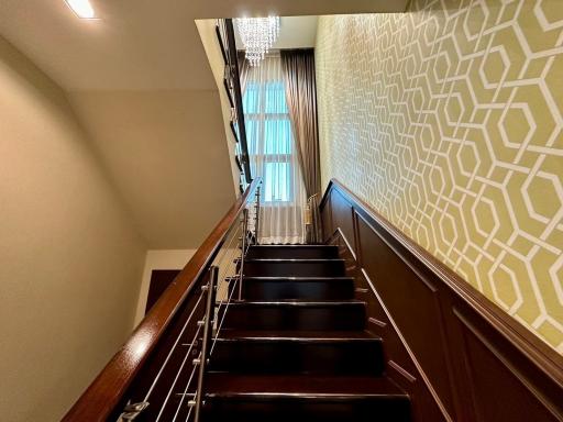 Elegant staircase with chandelier and patterned wallpaper