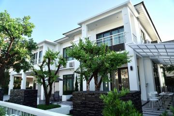 Modern two-story house with lush greenery and clear blue sky