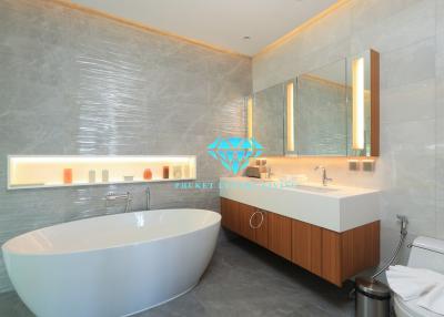 Spacious modern bathroom with freestanding tub, large mirror, and well-lit vanity area