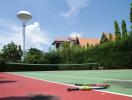 Outdoor tennis court with greenery and houses in the background