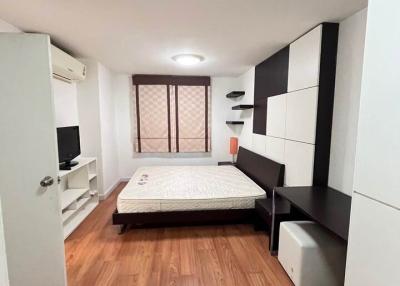 Modern bedroom with wooden flooring, large bed, and built-in storage