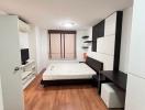 Modern bedroom with wooden flooring, large bed, and built-in storage