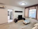 Modern living room with neutral tones, equipped with furniture and a flat-screen TV