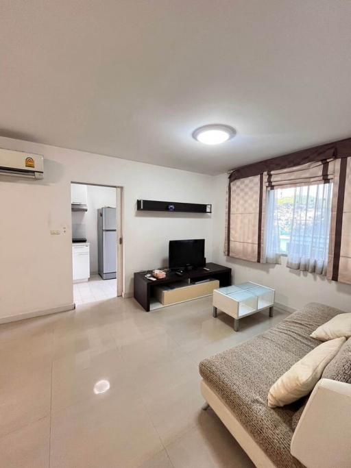 Modern living room with neutral tones, equipped with furniture and a flat-screen TV