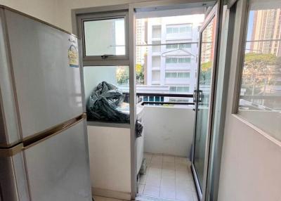 Compact balcony space with a refrigerator leading to the outdoors with urban view