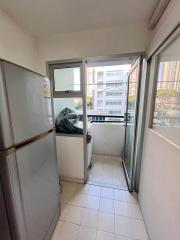 Compact balcony space with a refrigerator leading to the outdoors with urban view