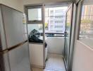 Compact balcony space with a refrigerator leading to the outdoors with urban view