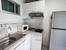 Compact, well-equipped kitchen with modern appliances and white cabinetry