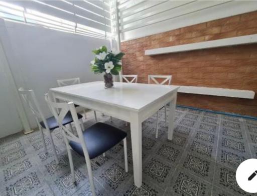 Cozy dining area with a white table and chairs, patterned tile flooring, and wooden accent wall