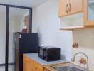 Compact modern kitchen with wooden cabinets and stainless steel sink