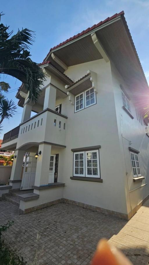 Exterior view of a two-story house with balconies and palm trees