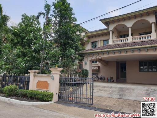 Exterior view of a two-story residential home with gated entrance and lush greenery