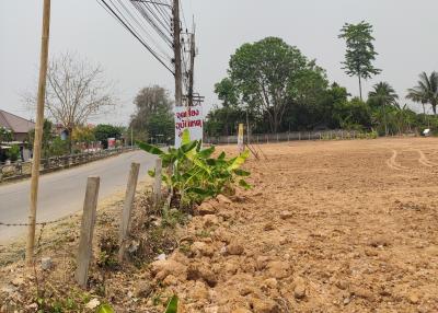 Empty residential land plot ready for construction with visible electric poles and paved road