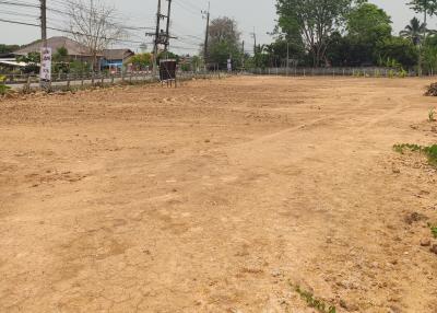 Vacant lot ready for construction with a dirt surface and surrounding greenery