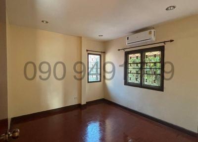 Spacious bedroom with glossy hardwood floors and an air conditioning unit