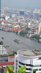 Overhead view of a bustling city with river traffic and helicopter pad on a building