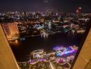 Stunning night view from a high-rise apartment balcony overlooking a vibrant cityscape and river