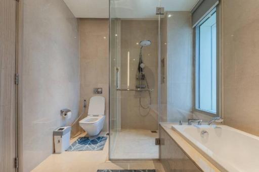 Modern bathroom with glass shower enclosure, bathtub, toilet, and large window