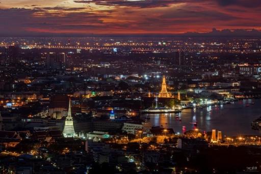 Panoramic view of a city at dusk with illuminated buildings and a river