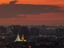 Panoramic view of the city skyline at dusk with lit buildings and a prominent monument