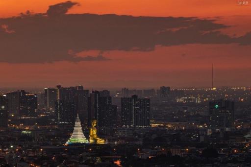 Panoramic view of the city skyline at dusk with lit buildings and a prominent monument