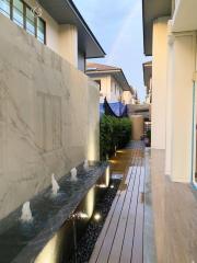 Elegant water feature in residential outdoor area with marble wall and wooden decking