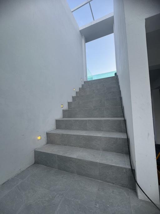 Modern staircase with gray tiles and wall-mounted lights