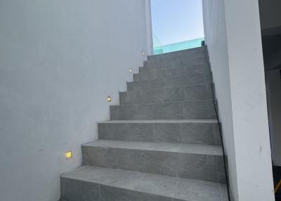 Modern staircase with gray tiles and wall-mounted lights