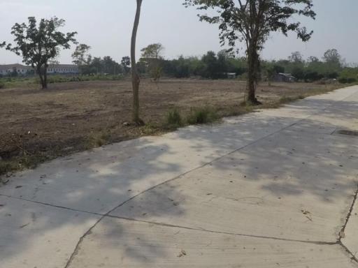 Empty plot of land next to a paved path with a clear sky