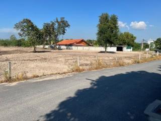 Wide empty lot with a building under construction in the background under a clear blue sky