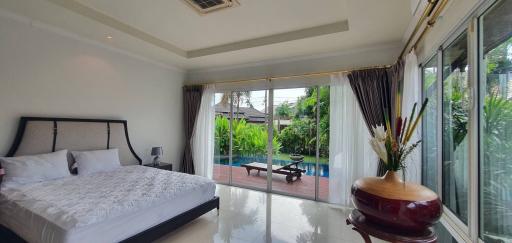 Spacious bedroom with a large bed, glossy tiled flooring, and access to the garden