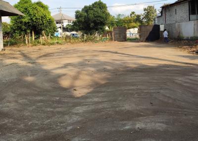 Spacious empty lot with potential for development or gardening near residential buildings