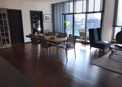 Spacious dining room with large table and modern chairs, floor-to-ceiling windows, and hardwood floors