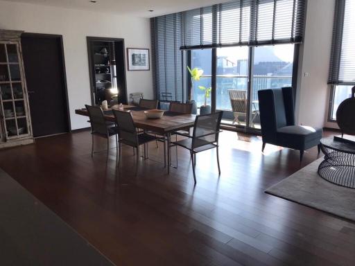 Spacious dining room with large table and modern chairs, floor-to-ceiling windows, and hardwood floors