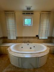 Spacious bathroom with large corner jacuzzi tub and natural light