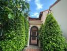 Elegant house entrance with brick walkway and lush greenery