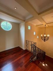 Elegant staircase with hardwood floors and unique round window