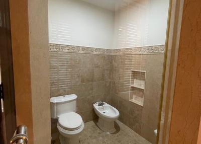 Compact bathroom with beige tiles, modern fixtures, and a bidet