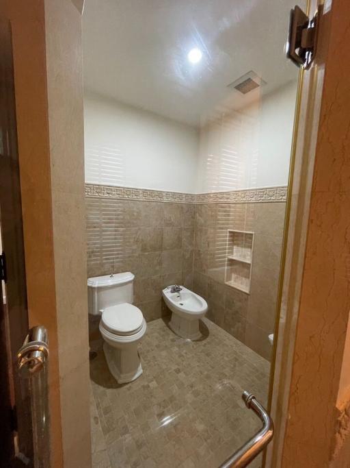 Compact bathroom with beige tiles, modern fixtures, and a bidet